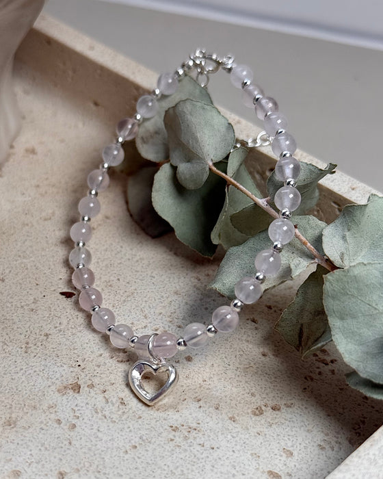 Rosenquarz-Armband mit Herzanhänger und 925er Silberperlen, zart rosé, verstellbar 18–22 cm, auf hellem Hintergrund.