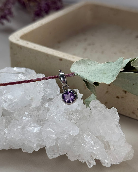 Nahaufnahme eines kleinen Amethyst-Anhängers mit Facettenschliff, eingefasst in 925er Silber, rund, feine Lichtreflexe