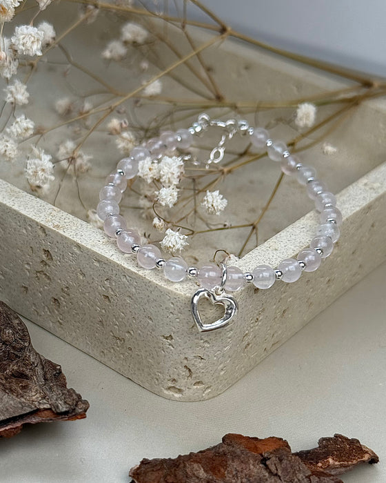 Nahaufnahme eines zarten Rosenquarz-Armbands mit Herzanhänger und Silberperlen, 4 mm Steine, elegante Handarbeit.