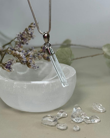 Natürlicher Aquamarin-Kristallanhänger mit 925er Silberöse, 2,8 cm lang, vor Selenitschale fotografiert.