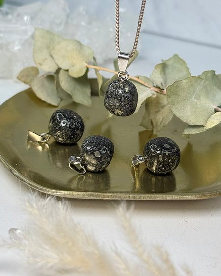 Pyritquarz-Anhänger mit goldenen Pyrit-Einschlüssen, ca. 1,4 cm, mit 925er Silberöse auf hellem Hintergrund.