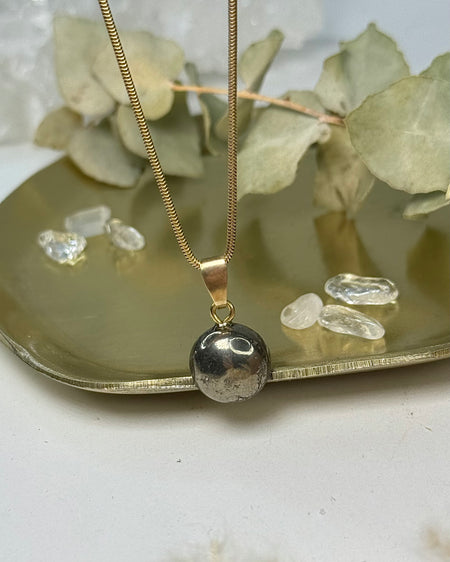 Pyrit-Cabochon-Anhänger mit 1,2 cm Durchmesser und vergoldeter 925er Silberöse auf hellem Hintergrund.