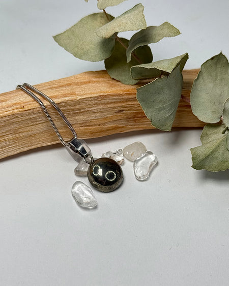 Pyrit-Cabochon-Anhänger mit 1,2 cm Durchmesser und 925er Silberöse auf hellem Hintergrund.