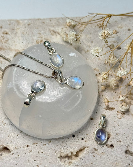 Zarter weißer Labradorit-Anhänger, filigran in 925er Silber gefasst, 0,9 cm, auf hellem Hintergrund.