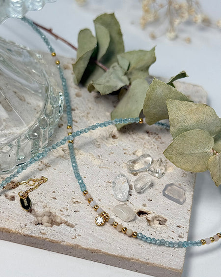 Feine Kette aus Apatit und Rhodonit mit zentralem Zirconia-Anhänger und vergoldeten 925er Silberelementen auf weißem Hintergrund.