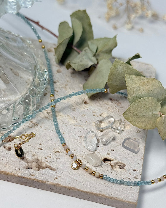 Feine Kette aus Apatit und Rhodonit mit zentralem Zirconia-Anhänger und vergoldeten 925er Silberelementen auf weißem Hintergrund.