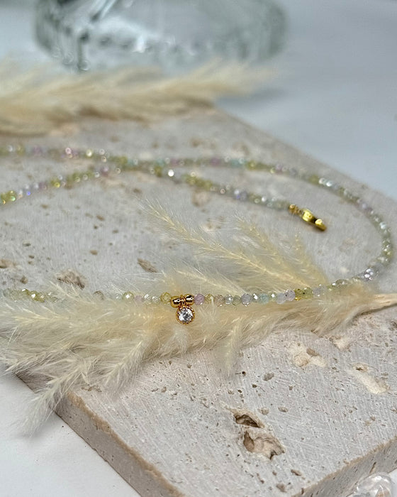 Nahaufnahme einer zarten Zirkon-Edelsteinkette mit funkelndem Zirconia-Anhänger und goldenen Details.