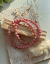 Nahaufnahme eines roséfarbenen Rhodochrosit-Armbands mit gemaserten Rundperlen und Silberakzent.