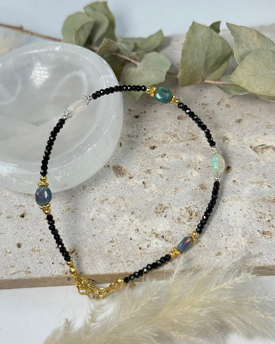 Feines Opalarmband aus schwarzem und weißem Opal mit Spinell und 925er Silber/vergoldeten Elementen auf hellem Hintergrund.